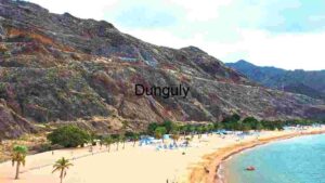 stunning beach with golden sands bordered by majestic, rugged cliffs under a partly cloudy sky