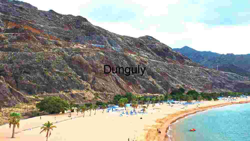 stunning beach with golden sands bordered by majestic, rugged cliffs under a partly cloudy sky