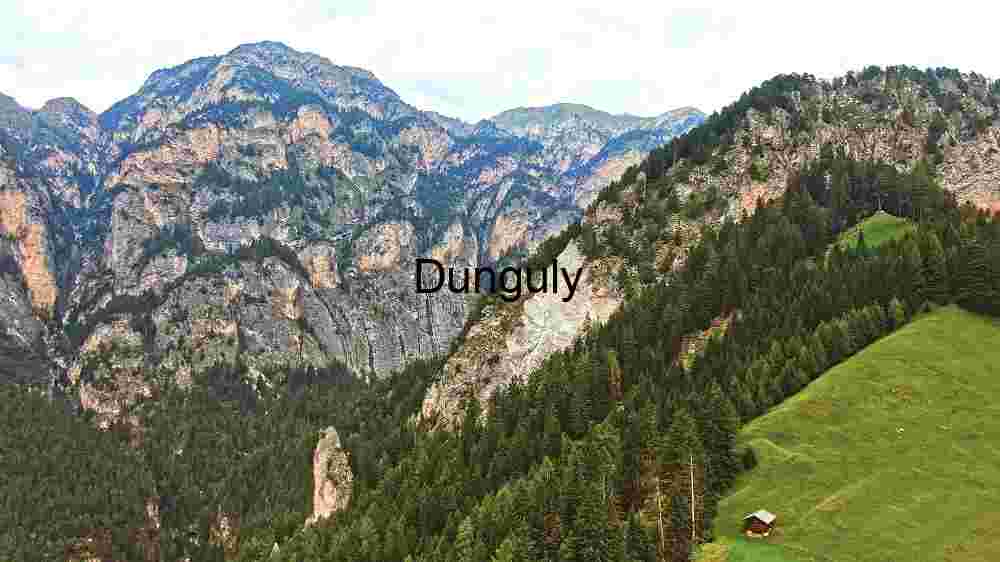 Alpine Majesty: A Solitary Hut Amidst Lush Meadows and Rugged Mountains