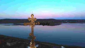 Golden Cross Overlooking Serene Lake at Dusk