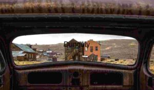 Abandoned Town Viewed Through Rusted Car Frame