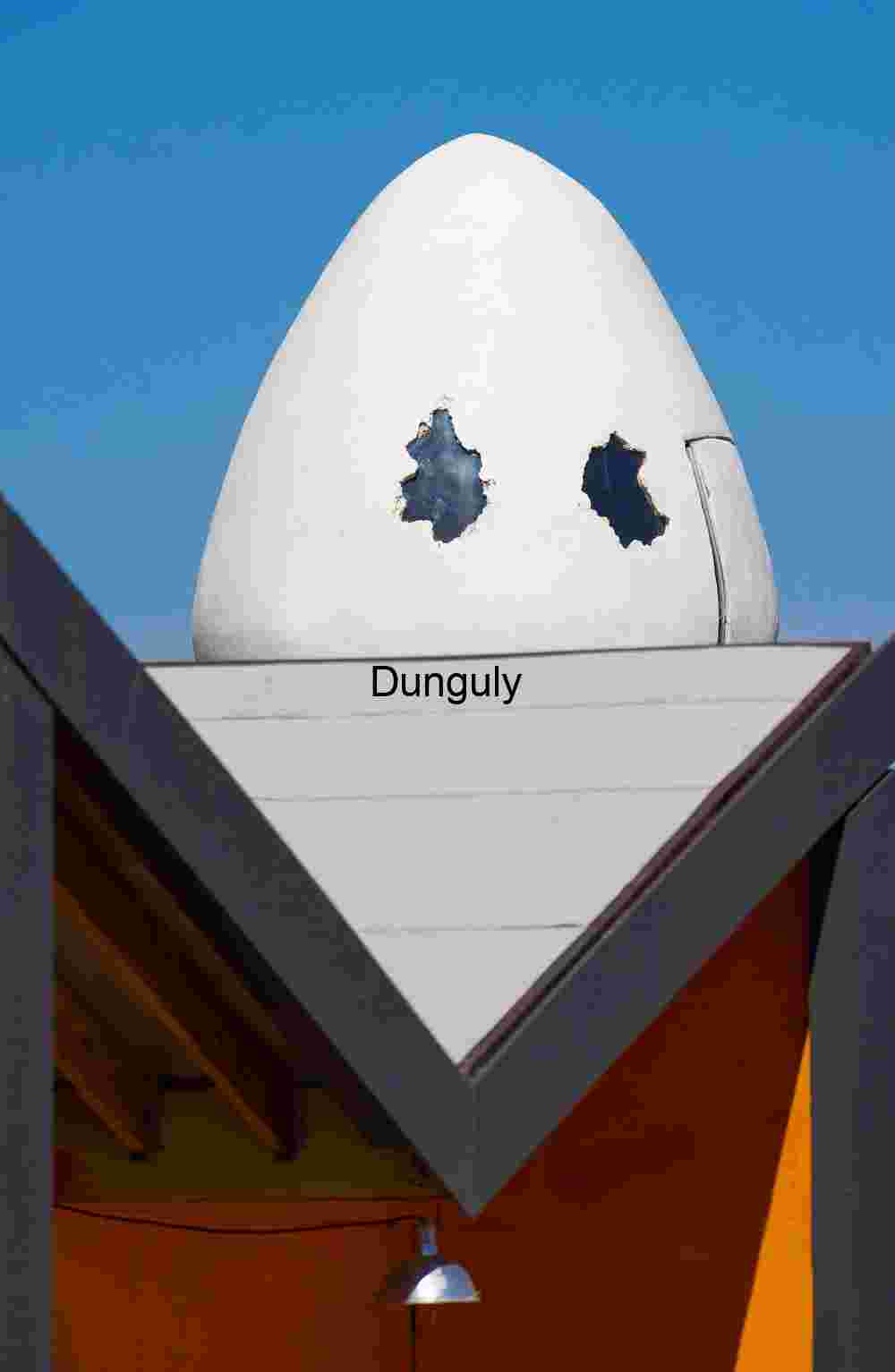 Whimsical Watcher: Egg-Shaped Sculpture atop Modern Facade