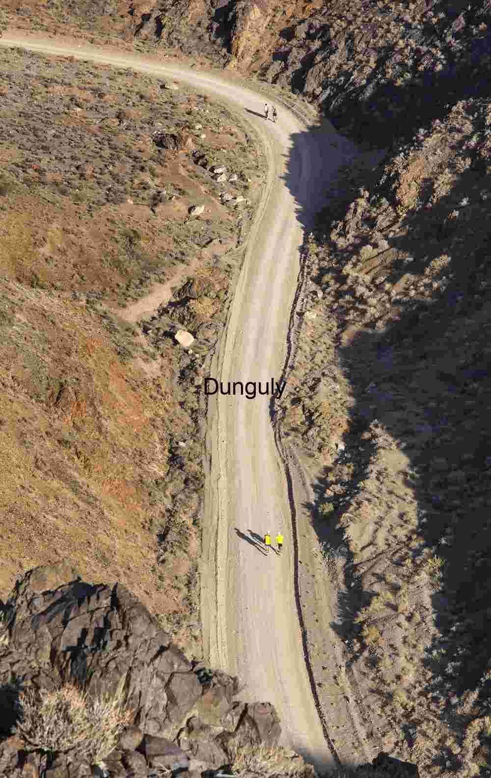 Winding Dirt Road Through Rocky Desert with Hikers in Bright Clothing