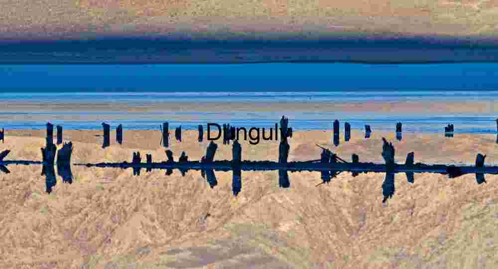 Wooden Posts Reflected in Desert Mirage with Mountain Backdrop