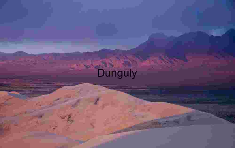 Sunlit Desert Dunes and Reddish Mountains Under Moody Sky