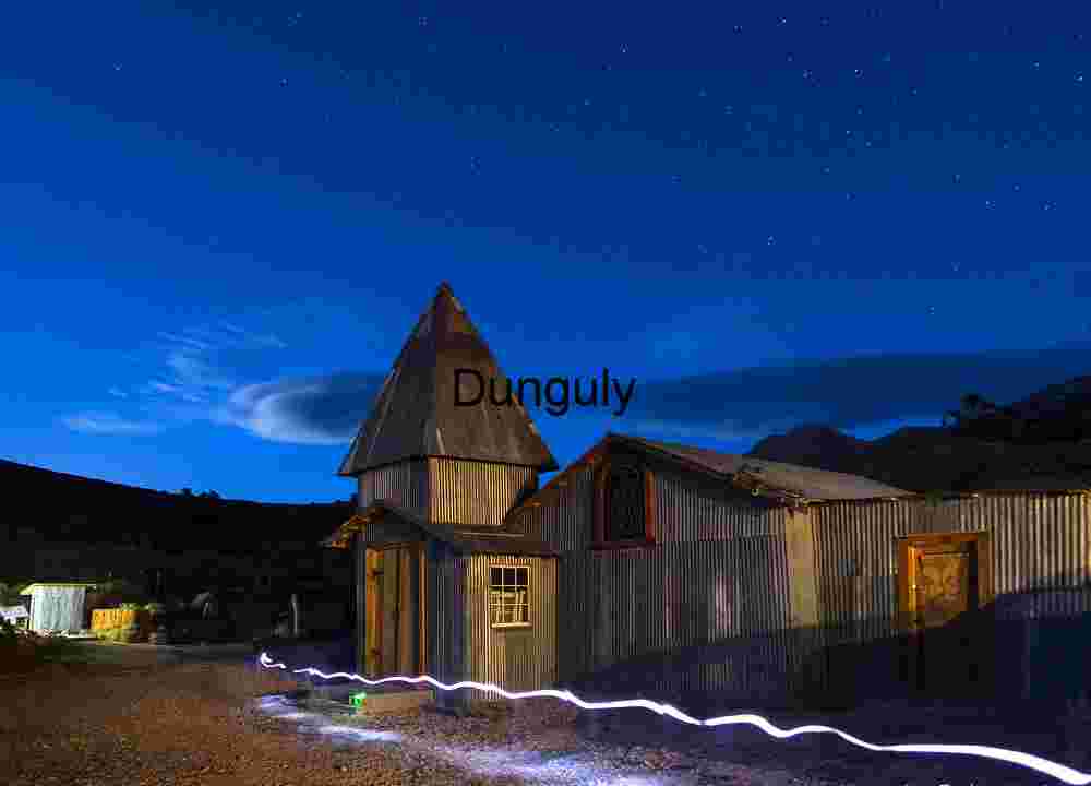 Rustic Ghost Town Under Starry Night Sky with Light Trail – Historic Mining Settlement Architecture