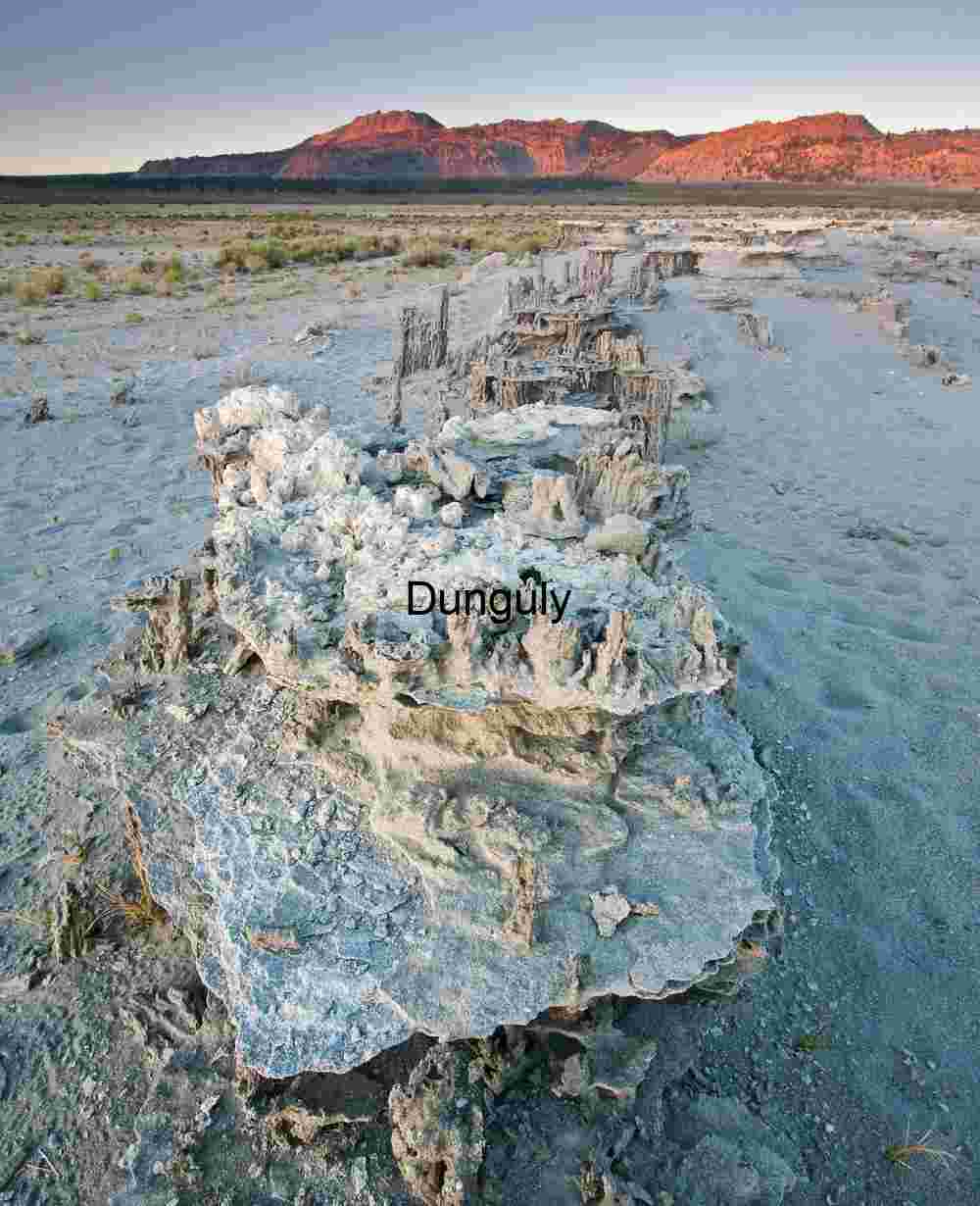 Sunlit Tufa Formations with Mountain Backdrop in Desert Basin