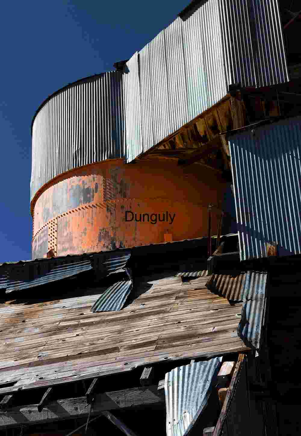 Rust and Flame: The Orange Tank Beneath a Broken Roof