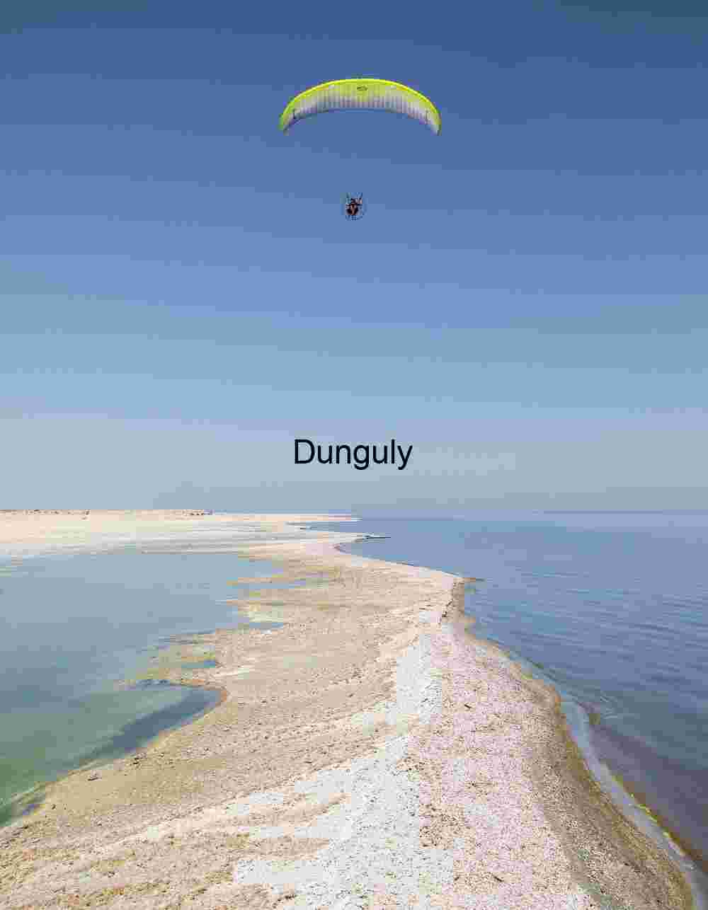 Paraglider Soaring Above Desert Peninsula Between Contrasting Waters