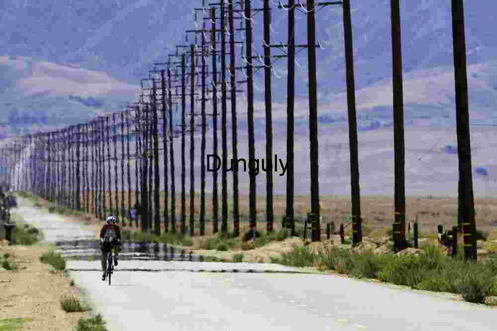 Cyclist on Desert Road Beneath Power Lines and Mirage
