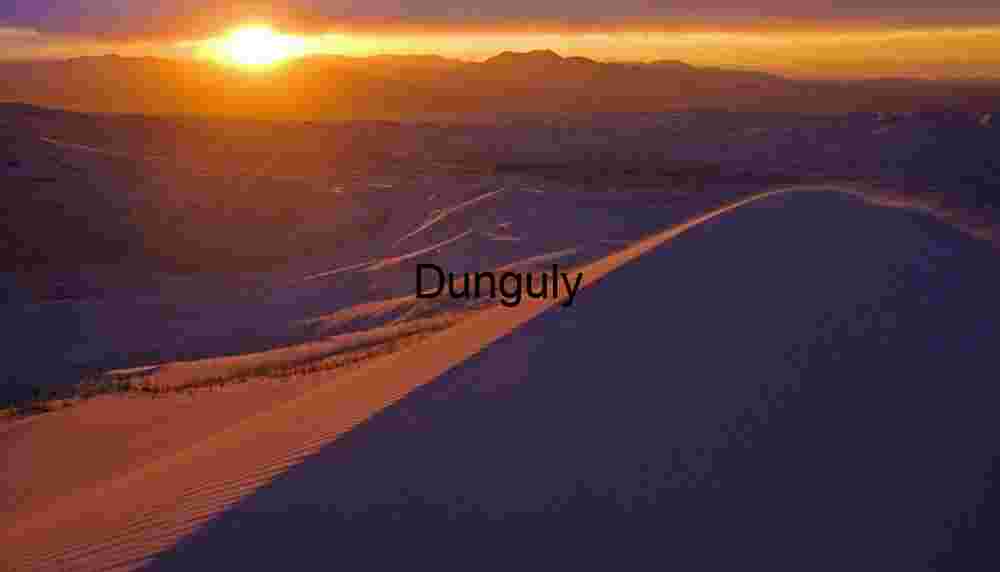 Sunset Over Sculpted Desert Dunes and Silhouetted Mountains