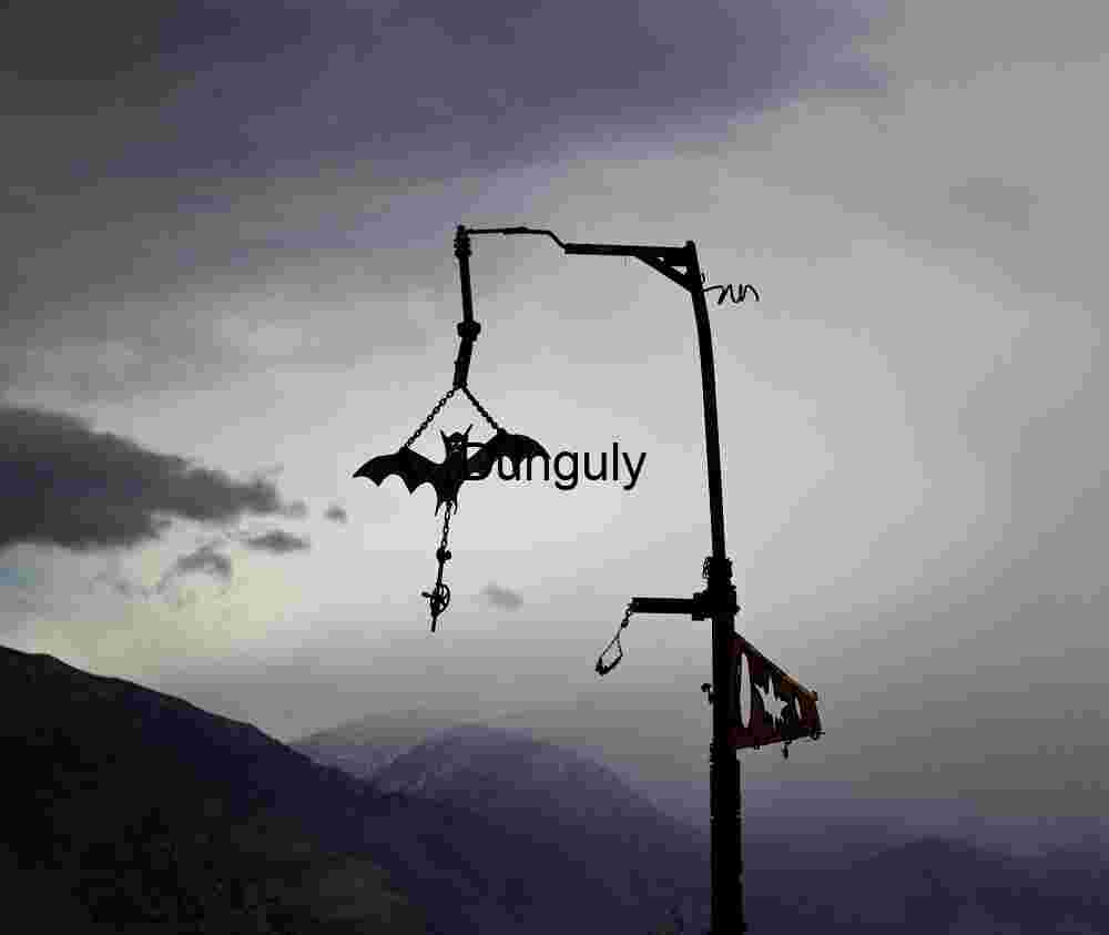 Metal Bat Sculpture Against Stormy Mountain Sky