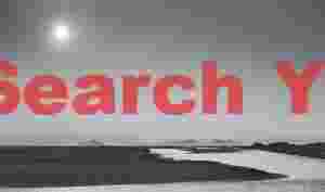 Distant view of Vestmannaeyjar with sun breaking through overcast sky; South Iceland