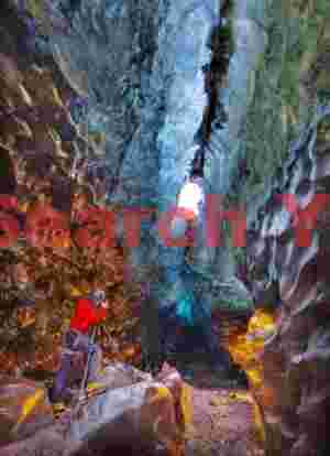Glacial Ice Formation at Golden ice cave with photographer in red, Vatnajokull, Iceland