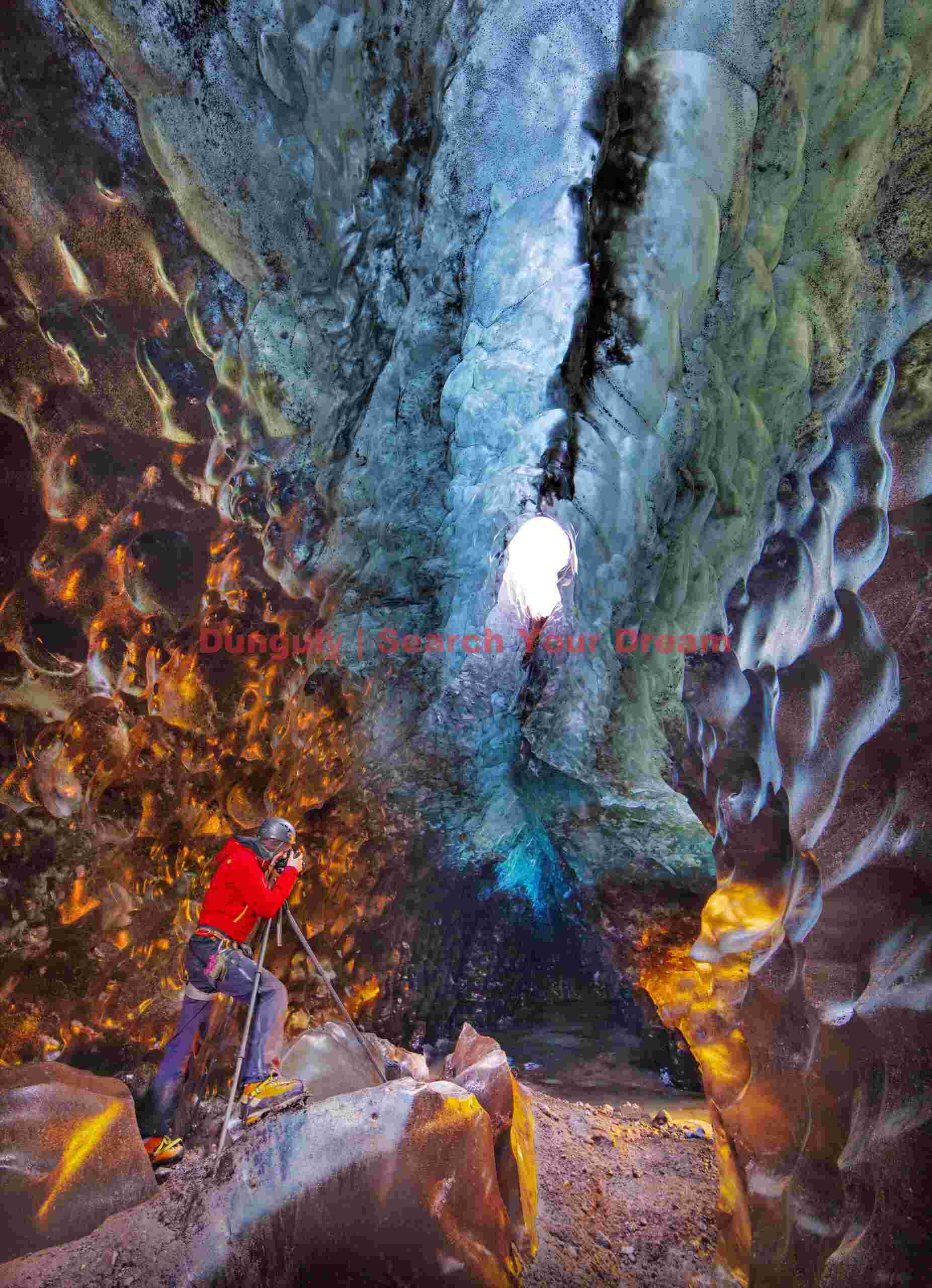 Glacial Ice Formation at Golden ice cave with photographer in red, Vatnajokull, Iceland