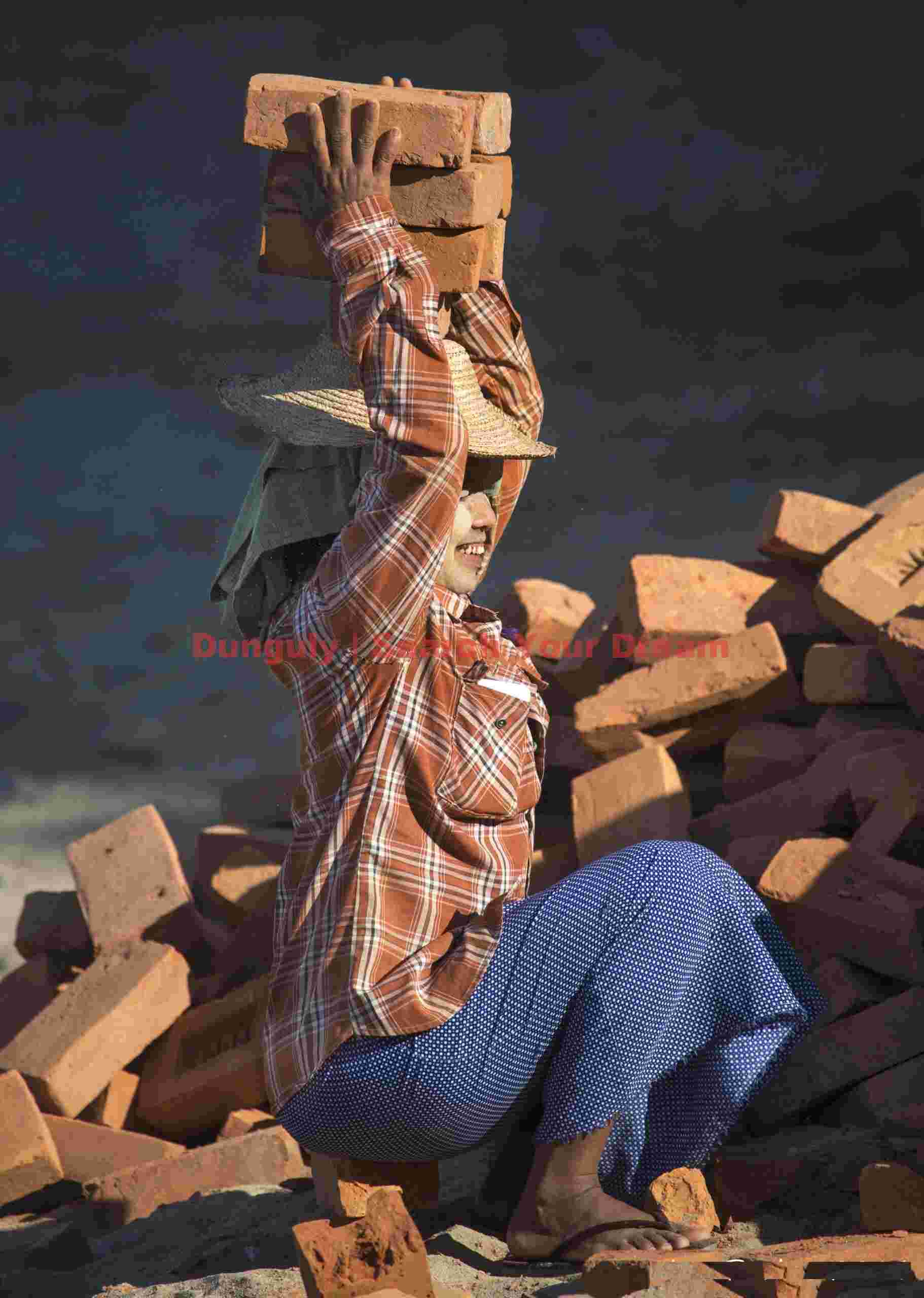 Girl carrying bricks on her head