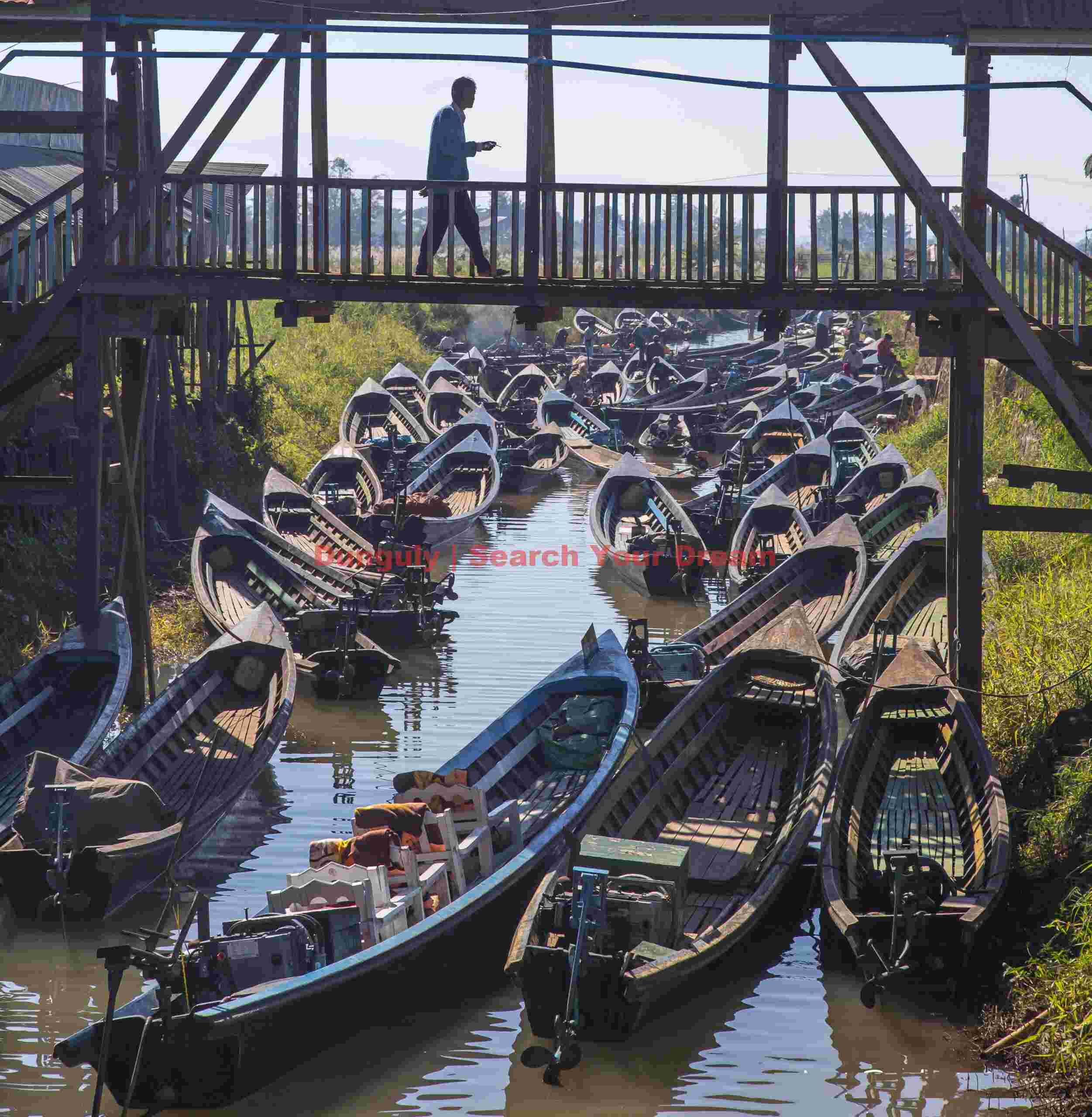 Man crossing bridge with multitude of boats