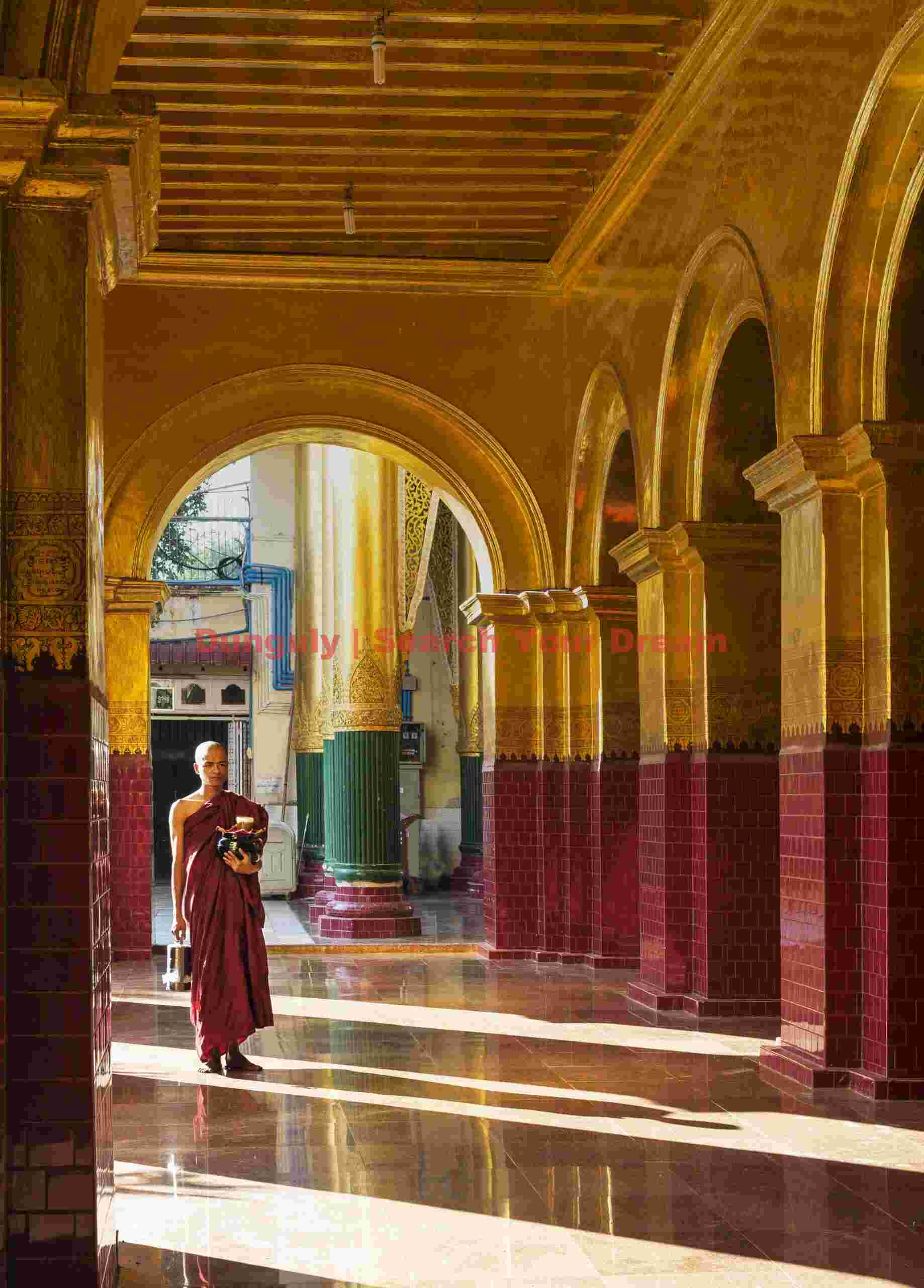 Monk walking along golden-arched passage