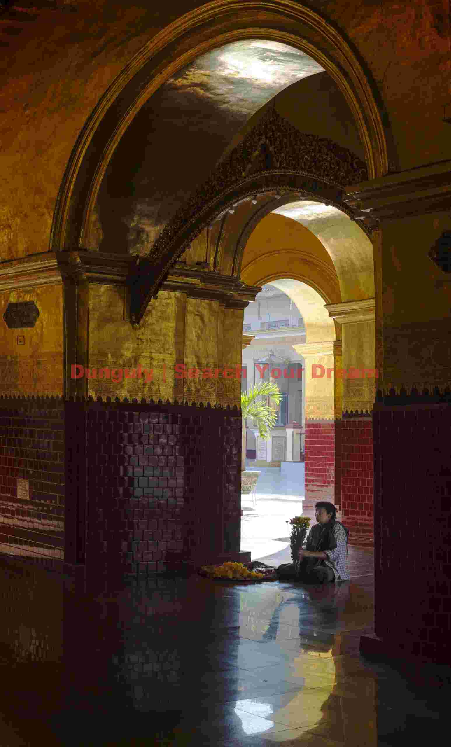 Worshiper with flowers sitting in archway